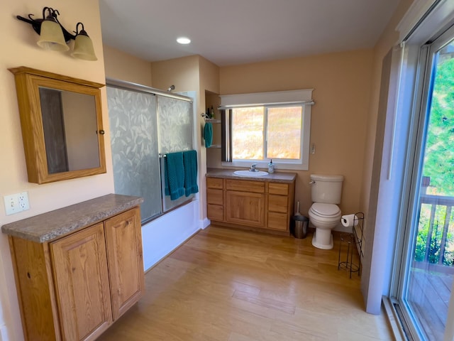 full bath featuring toilet, a wealth of natural light, and wood finished floors