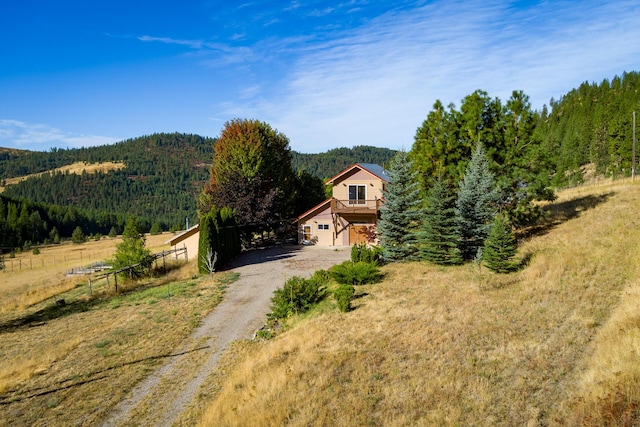 view of front of home with driveway, a forest view, and fence