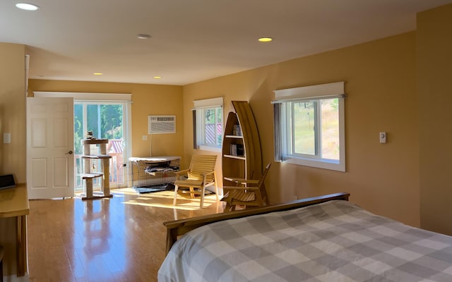 bedroom featuring recessed lighting, multiple windows, an AC wall unit, and wood finished floors