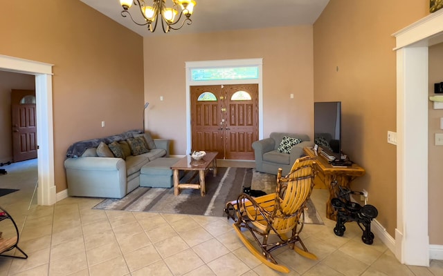 living room featuring a high ceiling, light tile patterned floors, baseboards, and an inviting chandelier