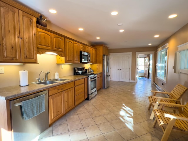 kitchen with light tile patterned floors, recessed lighting, appliances with stainless steel finishes, brown cabinetry, and a sink