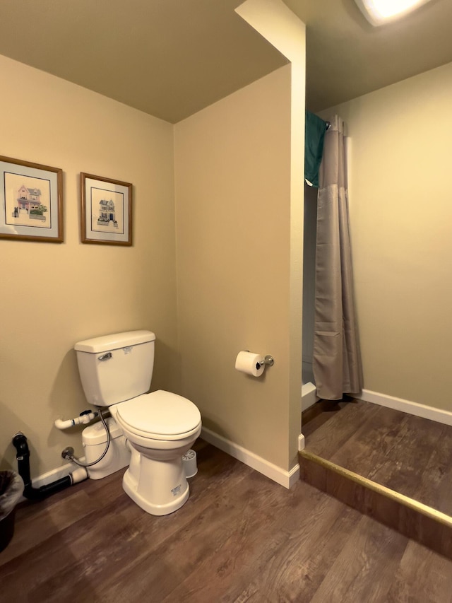 bathroom with hardwood / wood-style floors, a shower with curtain, and toilet