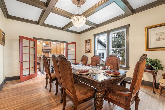 dining area featuring light hardwood / wood-style floors, beam ceiling, a notable chandelier, and coffered ceiling