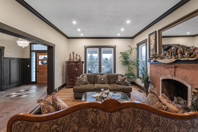 living room featuring a fireplace, light hardwood / wood-style floors, an inviting chandelier, and ornamental molding