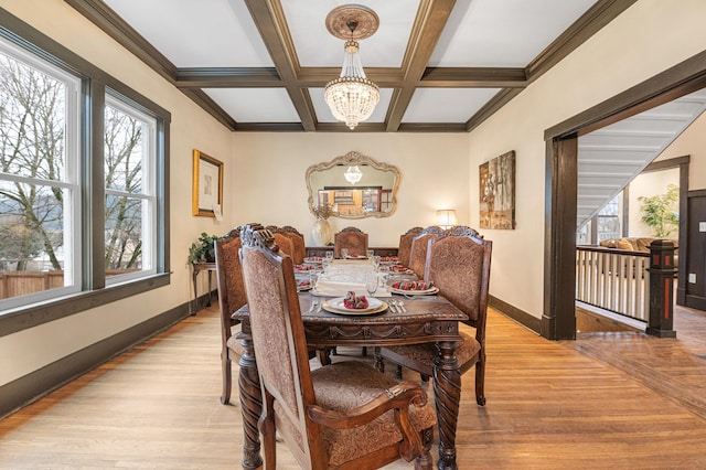 dining space featuring crown molding, coffered ceiling, a chandelier, beam ceiling, and light hardwood / wood-style flooring