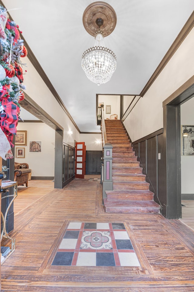 staircase with parquet flooring, ornamental molding, and an inviting chandelier