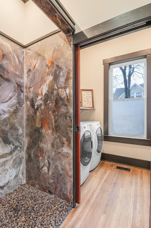 clothes washing area with washing machine and clothes dryer and light hardwood / wood-style floors