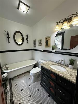 bathroom featuring toilet, vanity, tile patterned floors, and a bathtub