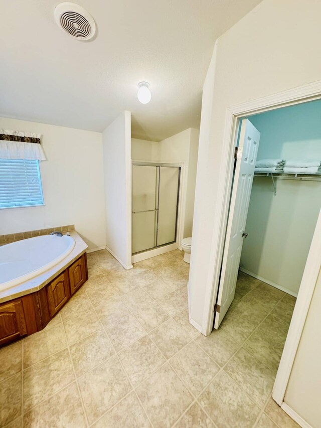 211 8th Ave, Ione, WA 99139 - bathroom with a shower stall, a bath, a walk in closet, toilet, and tile patterned floors