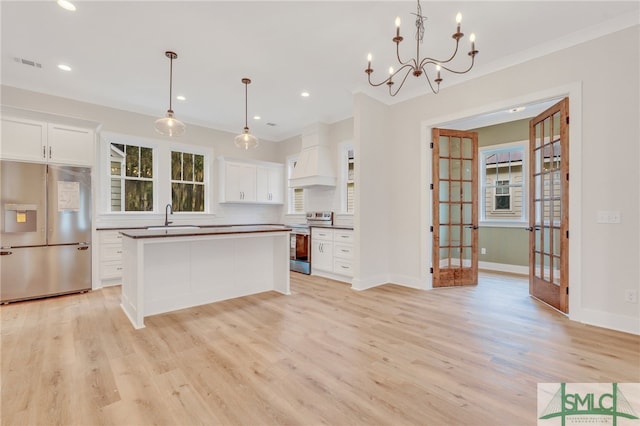 kitchen with white cabinets, light hardwood / wood-style floors, stainless steel appliances, and decorative light fixtures