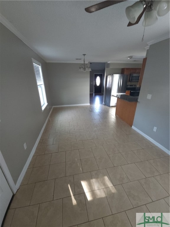 unfurnished living room featuring crown molding, ceiling fan with notable chandelier, and light tile floors