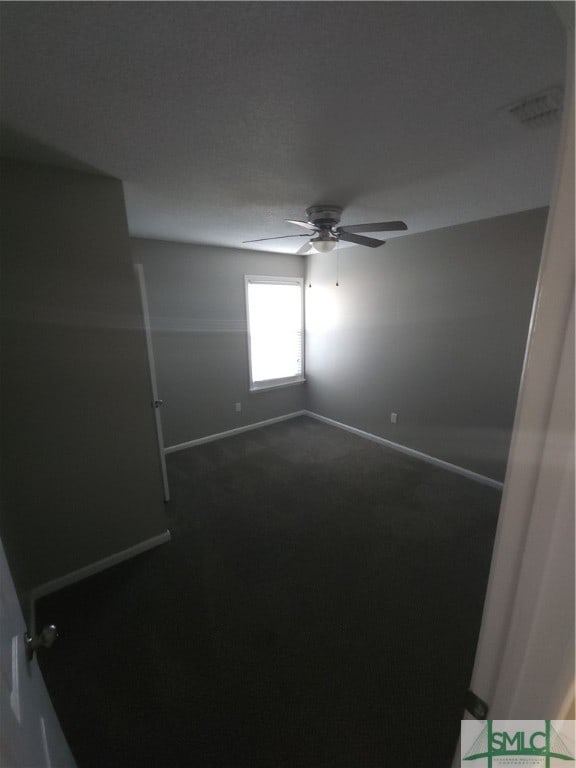 empty room featuring dark colored carpet and ceiling fan