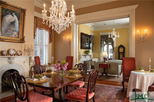 dining space with a fireplace, ornamental molding, a notable chandelier, and hardwood / wood-style flooring