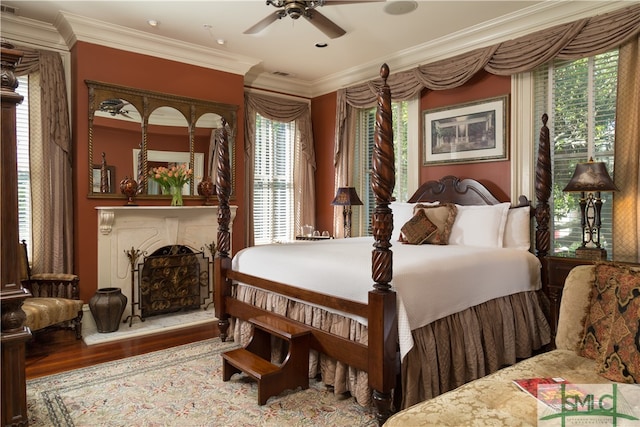 bedroom with wood-type flooring, multiple windows, ornamental molding, and ceiling fan