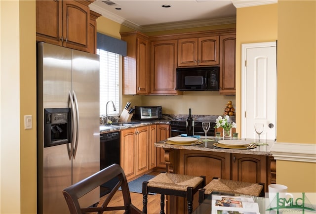 kitchen featuring black appliances, a kitchen bar, dark stone countertops, and ornamental molding