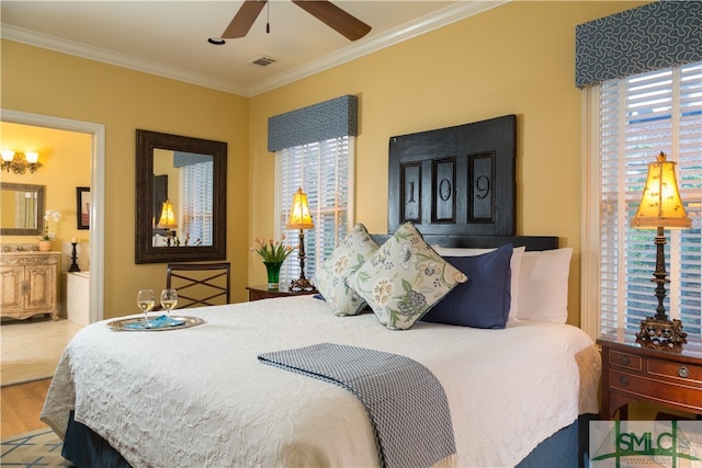 bedroom featuring hardwood / wood-style flooring, ensuite bathroom, crown molding, and multiple windows