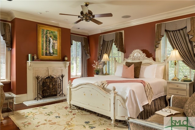 bedroom with hardwood / wood-style floors, multiple windows, ornamental molding, and ceiling fan