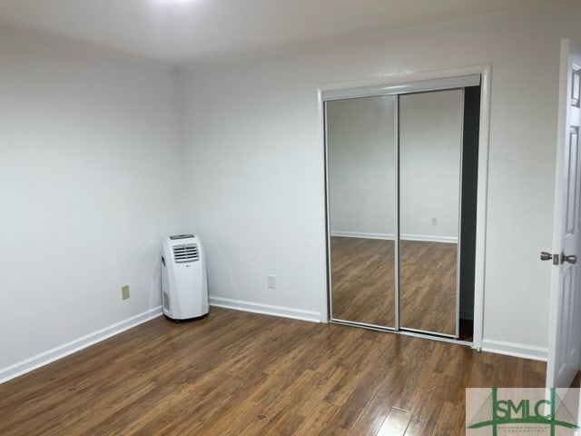 unfurnished bedroom featuring dark wood-type flooring and a closet