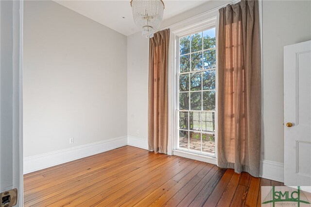 unfurnished room with hardwood / wood-style floors and a chandelier