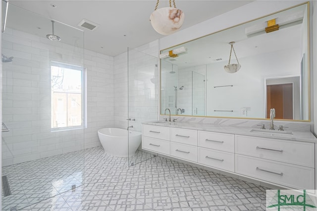 bathroom with visible vents, double vanity, a freestanding bath, a sink, and a shower stall