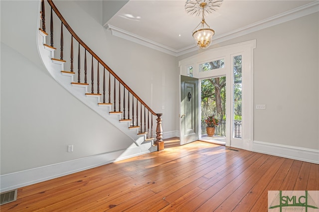 foyer with an inviting chandelier, light hardwood / wood-style flooring, and crown molding