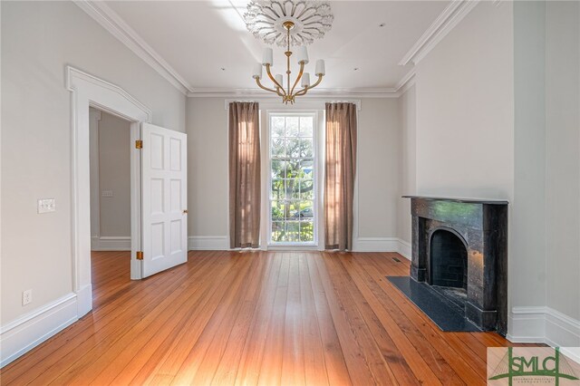 unfurnished living room with a chandelier, light hardwood / wood-style flooring, and crown molding