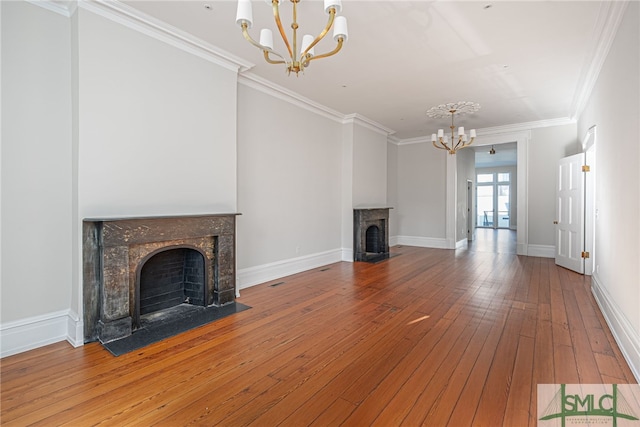 unfurnished living room with a fireplace with flush hearth, a notable chandelier, ornamental molding, and hardwood / wood-style flooring