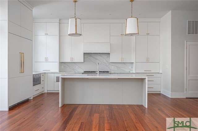 kitchen with white cabinetry, dark hardwood / wood-style flooring, hanging light fixtures, and a center island with sink