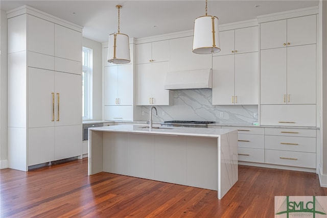 kitchen featuring a kitchen island with sink, dark wood-type flooring, sink, decorative light fixtures, and white cabinets