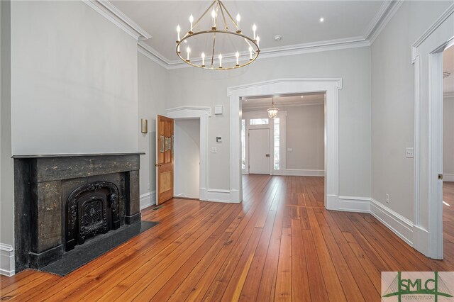 unfurnished living room featuring a notable chandelier, wood-type flooring, and ornamental molding