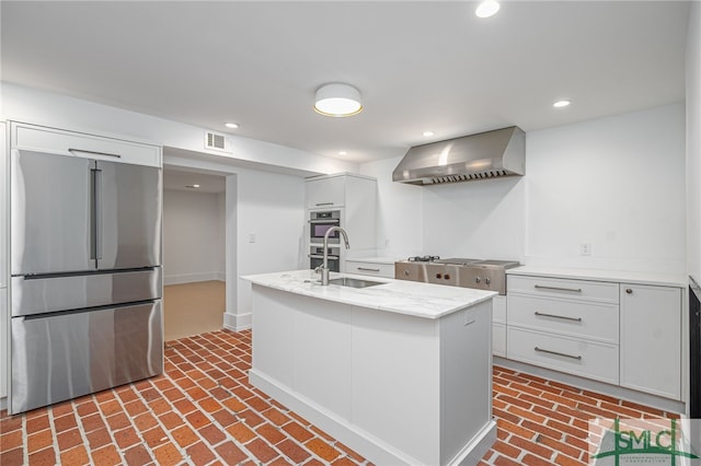 kitchen with white cabinets, sink, wall chimney range hood, and stainless steel appliances