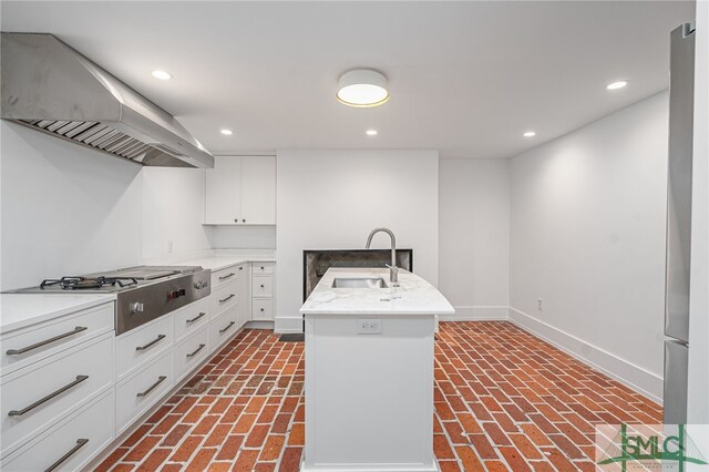 kitchen with sink, stainless steel gas cooktop, extractor fan, a kitchen island with sink, and white cabinets