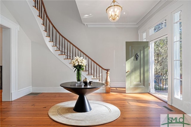 entryway with visible vents, baseboards, stairway, a notable chandelier, and wood-type flooring