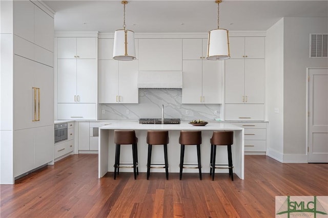 kitchen with a breakfast bar, tasteful backsplash, visible vents, and white cabinetry