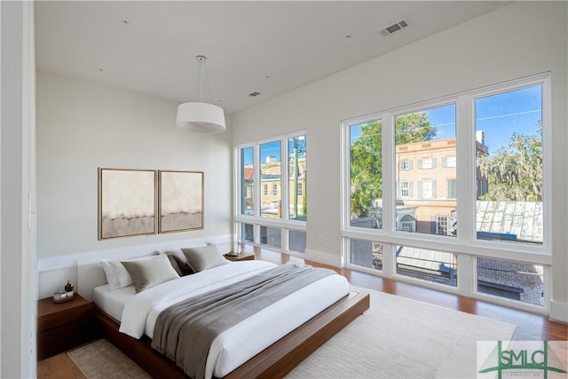 bedroom featuring wood finished floors, visible vents, and baseboards