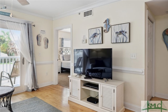 living room featuring ornamental molding, light wood-type flooring, ceiling fan, and a wealth of natural light