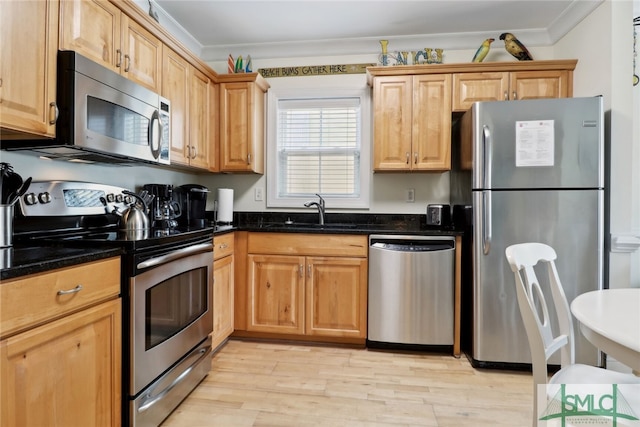 kitchen with light hardwood / wood-style floors, dark stone counters, appliances with stainless steel finishes, crown molding, and sink