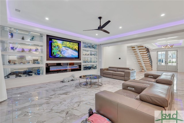 tiled cinema featuring a raised ceiling, ceiling fan with notable chandelier, and french doors