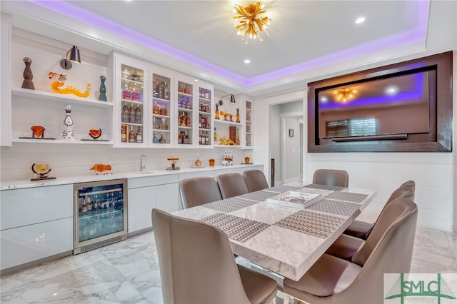 tiled dining space with a raised ceiling and beverage cooler