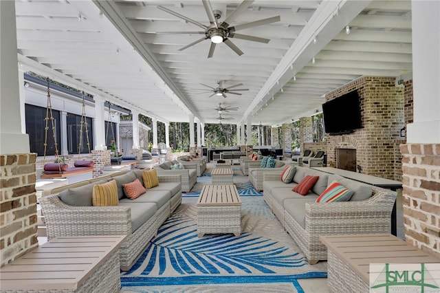 sunroom featuring plenty of natural light, a brick fireplace, ceiling fan, and beamed ceiling