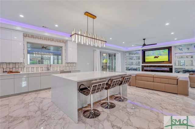 kitchen with white cabinets, ceiling fan with notable chandelier, light tile floors, and a kitchen breakfast bar