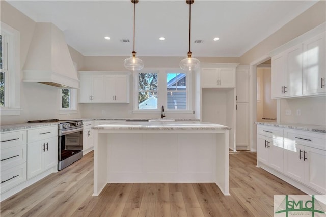 kitchen with pendant lighting, white cabinets, stainless steel range with electric cooktop, light stone counters, and custom range hood