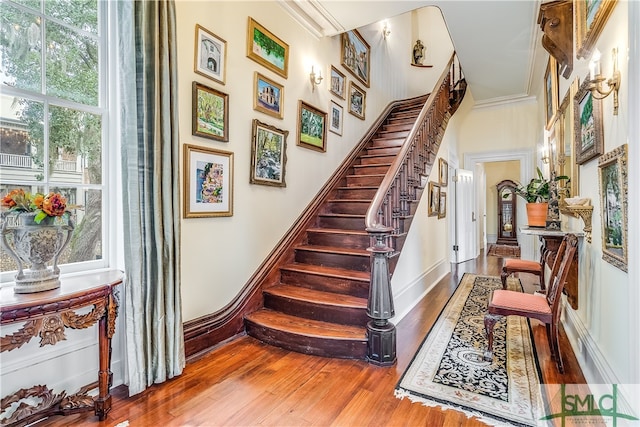 stairs with crown molding and hardwood / wood-style flooring