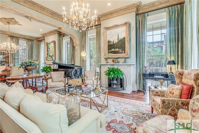 living room featuring a wealth of natural light, an inviting chandelier, crown molding, and hardwood / wood-style flooring