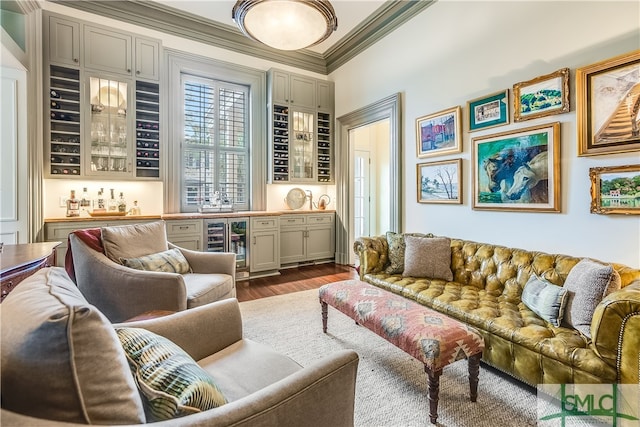 living room with indoor bar, beverage cooler, ornamental molding, and dark hardwood / wood-style floors