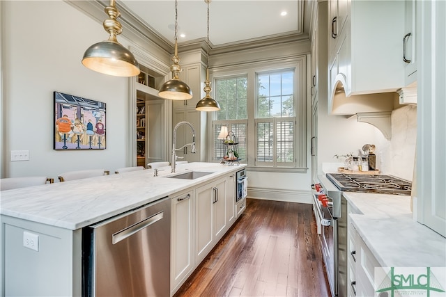 kitchen with a center island with sink, dark wood-type flooring, light stone counters, hanging light fixtures, and appliances with stainless steel finishes