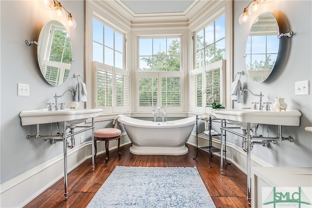 bathroom with a bath to relax in, ornamental molding, and hardwood / wood-style floors