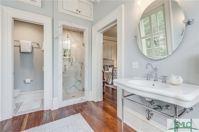 bathroom featuring a shower with door, toilet, and hardwood / wood-style floors