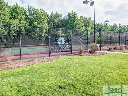 view of tennis court featuring fence and a lawn