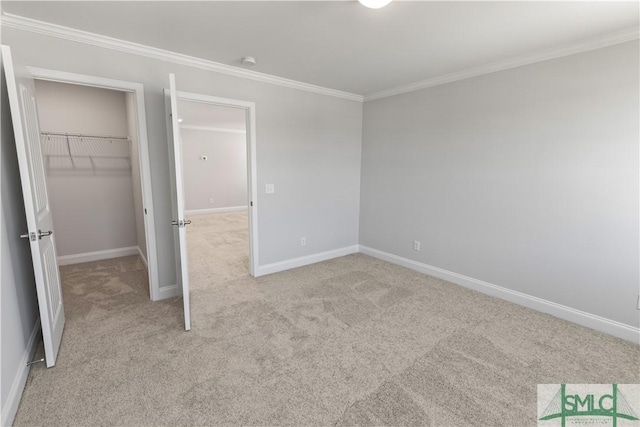 unfurnished bedroom with a spacious closet, baseboards, crown molding, and light colored carpet